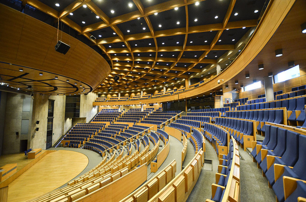 Image of a large scale auditorium with two ranks of seats arranged in a half circle.