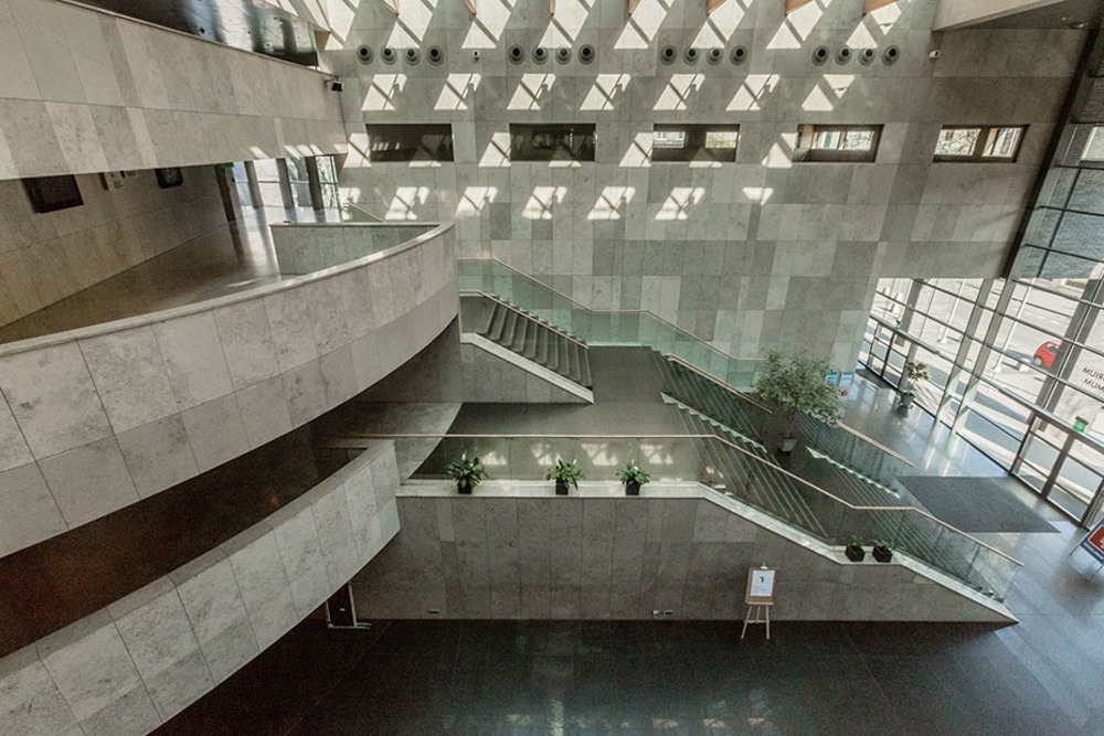 Image the atrium of the venue, consisting of indoor balconys and stairs in a brutalist style
